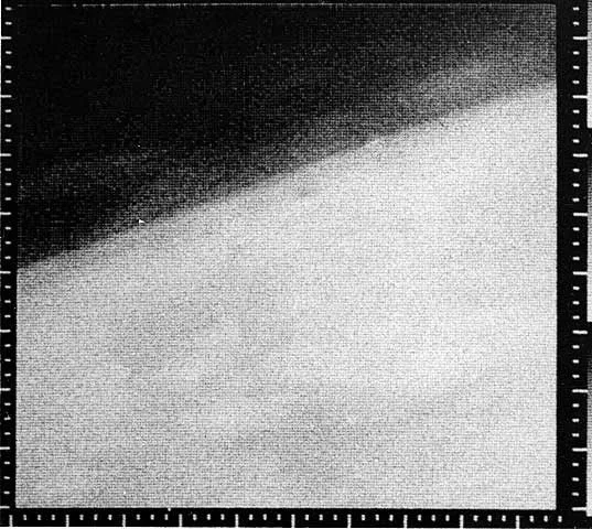 Image granuleuse de Mars avec une zone sombre au-dessus d’une grande zone claire oblique, entourée de marques de repérage.