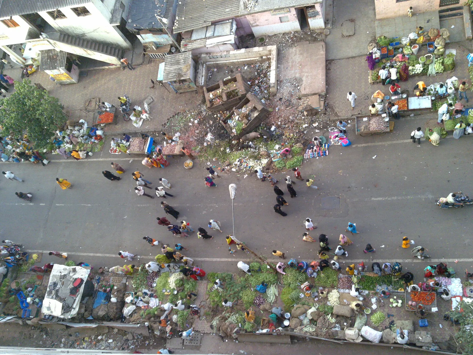 Rue principale de Dharavi à Mumbai en août 2009, avec marché, commerces, circulation et bâti dense.