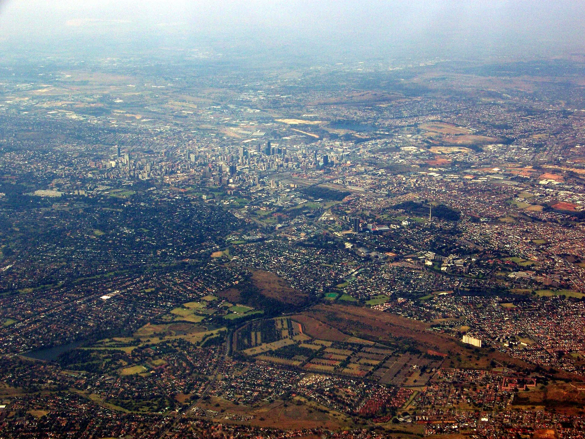 Vue aérienne de Johannesburg vers l'est, montrant un tissu urbain étendu et des axes de circulation.