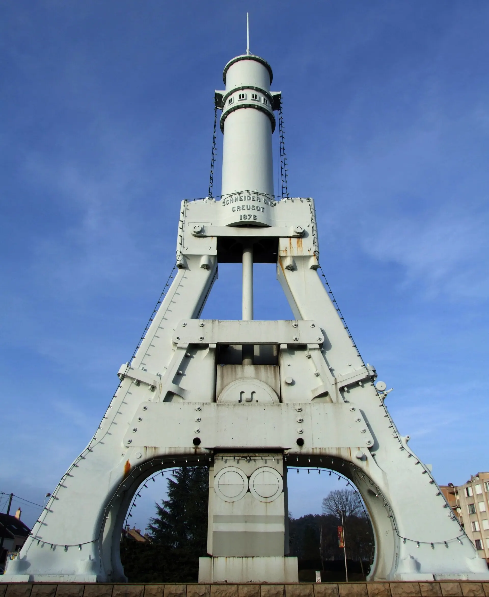 Photographie du marteau-pilon géant du Creusot conservé comme monument industriel avec un visiteur donnant l’échelle