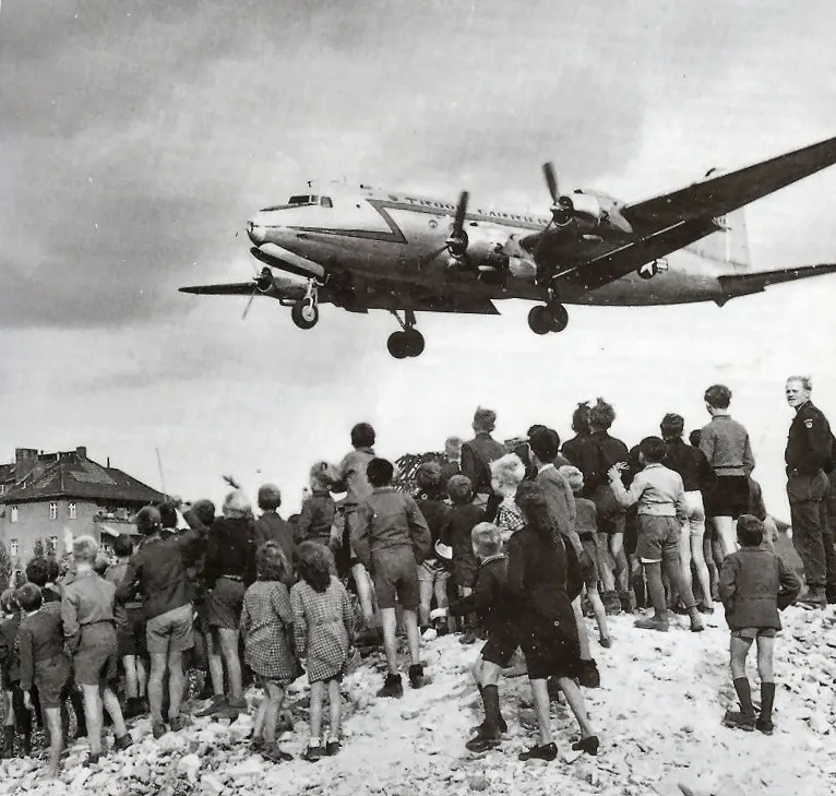 Photographie d’enfants observant un avion américain pendant le pont aérien de Berlin en 1948