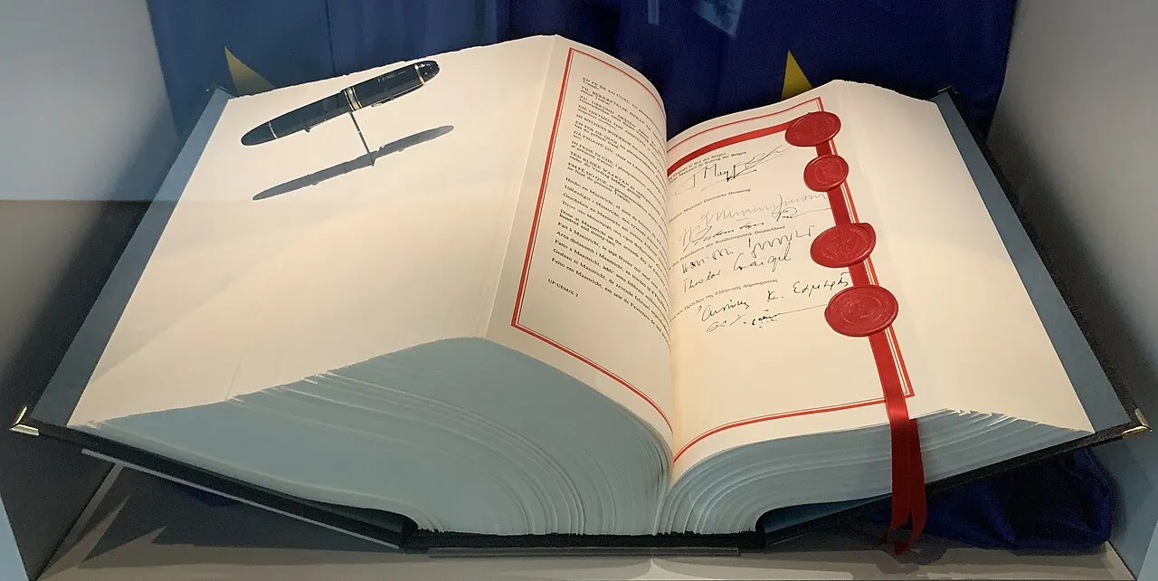 Exemplaire ouvert du traité de Maastricht présenté dans un musée, avec pages imprimées et rubans aux couleurs européennes